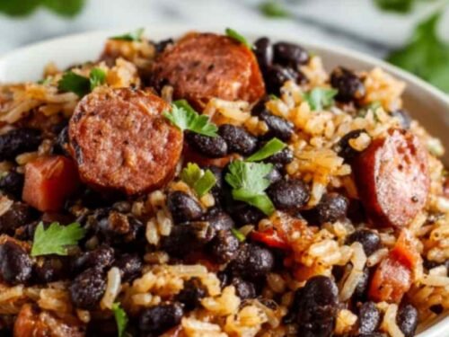 Black beans and rice with sausage in a large skillet garnished with fresh cilantro