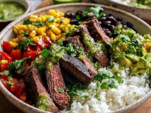 Cilantro lime steak bowls with sliced grilled flank steak, rice, black beans, corn, tomatoes, and avocado