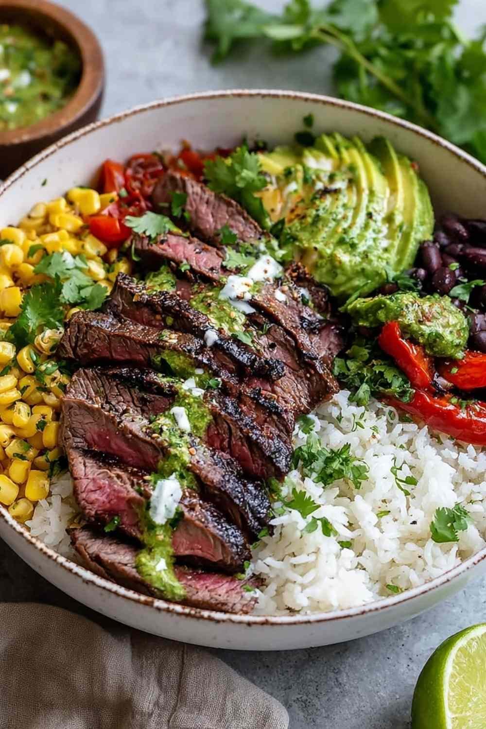Cilantro lime steak bowls with sliced grilled flank steak, rice, black beans, corn, tomatoes, and avocado